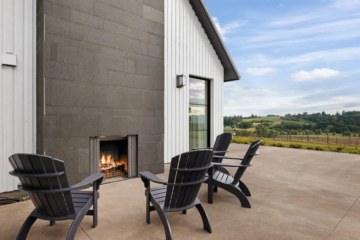 A set of Adirondack chairs encircles a fireplace on a patio with a sweeping landscape view. The space feels calm and intimate, perfect for unwinding after outdoor activities or enjoying quiet contemplation while taking in natural vistas.