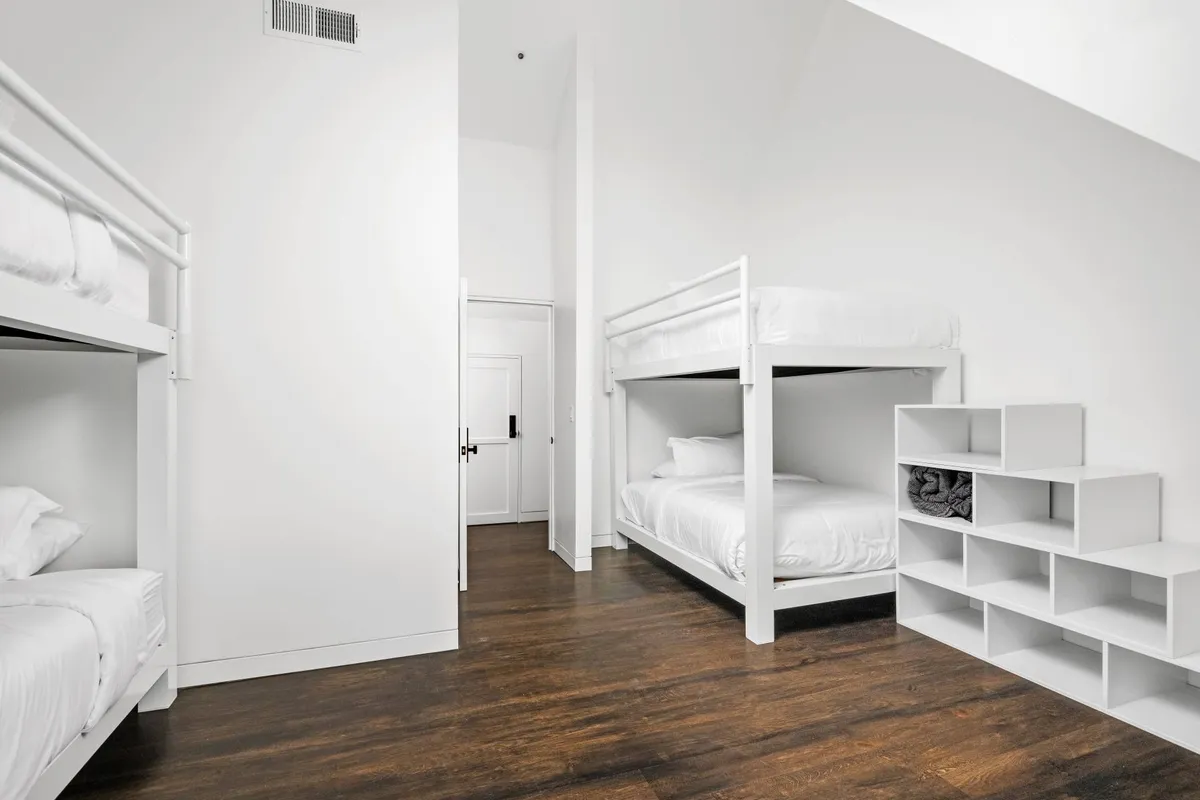 A casual and comfortable bunk room with neatly organized bunk beds and shelving—an inviting haven for kids and young guests. The space is designed for shared sleepovers, playful mornings, and relaxed reading.