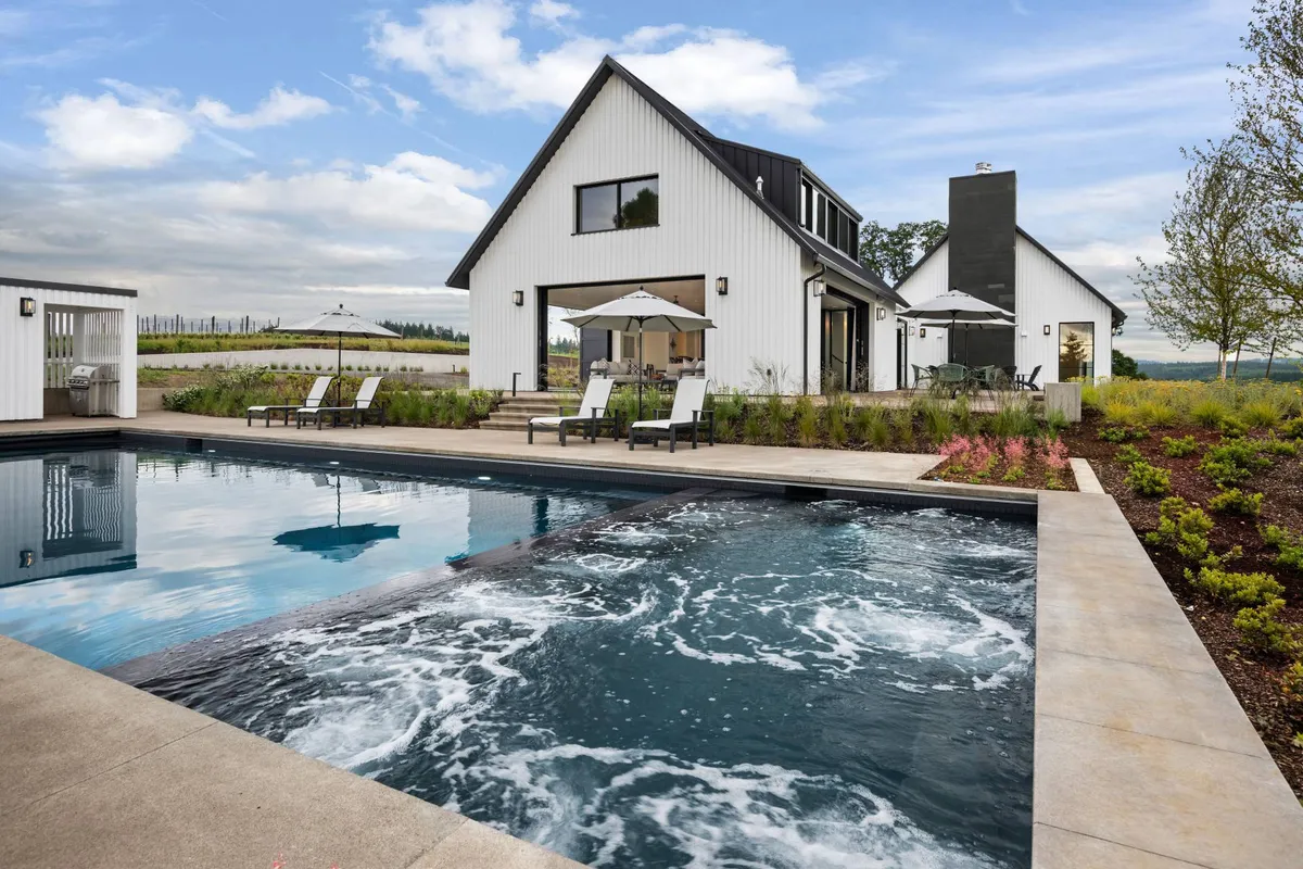 This exterior image features the estate's swimming pool, patio area, house facade, and surrounding landscaping. The scene highlights the integration of comfortable outdoor living with the natural environment, suggesting a property that values green space and relaxation in harmony with nature.
