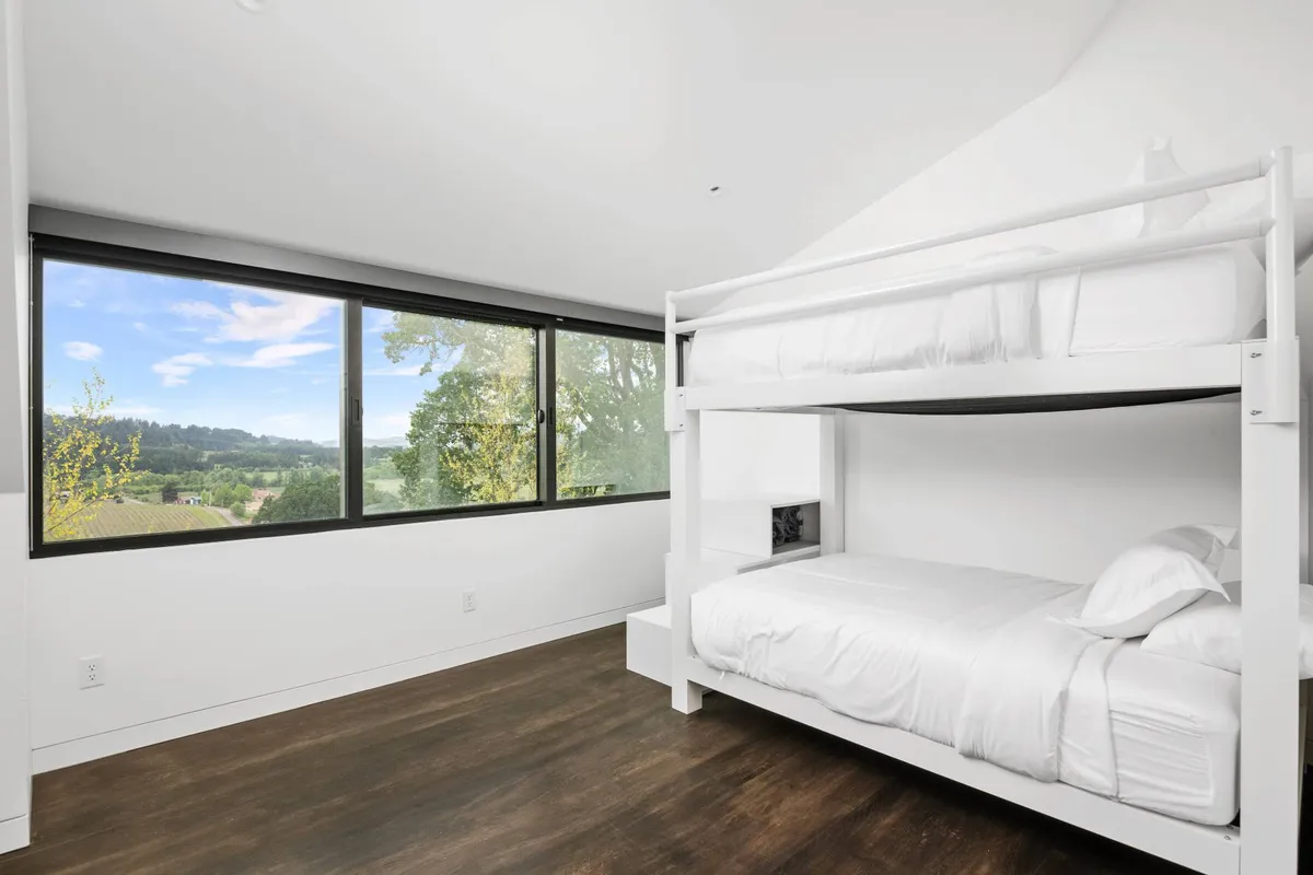 A cozy bunk room equipped with full-over-full bunk beds, large windows framing scenic views, and a casual, welcoming vibe perfect for kids or groups sharing the space.