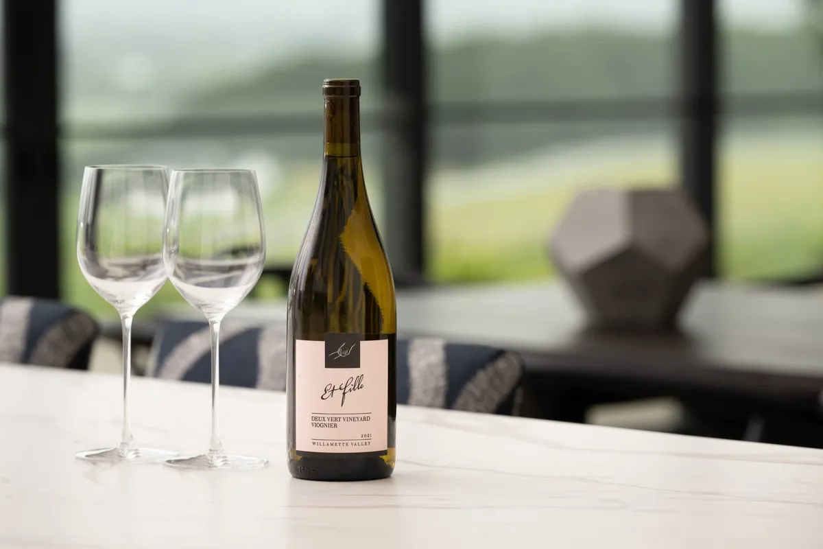 A close-up of a dining table elegantly set with a wine bottle and glasses, ideal for wine tastings or intimate dining experiences. The setting feels relaxed yet refined, perfect for social gatherings.