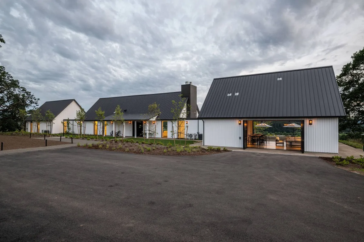 This exterior shot presents the estate's modern architecture, landscaped garden, large windows, and an inviting outdoor seating area. The peaceful scene suggests opportunities for outdoor enjoyment, gathering with family, and appreciating the surrounding environment.